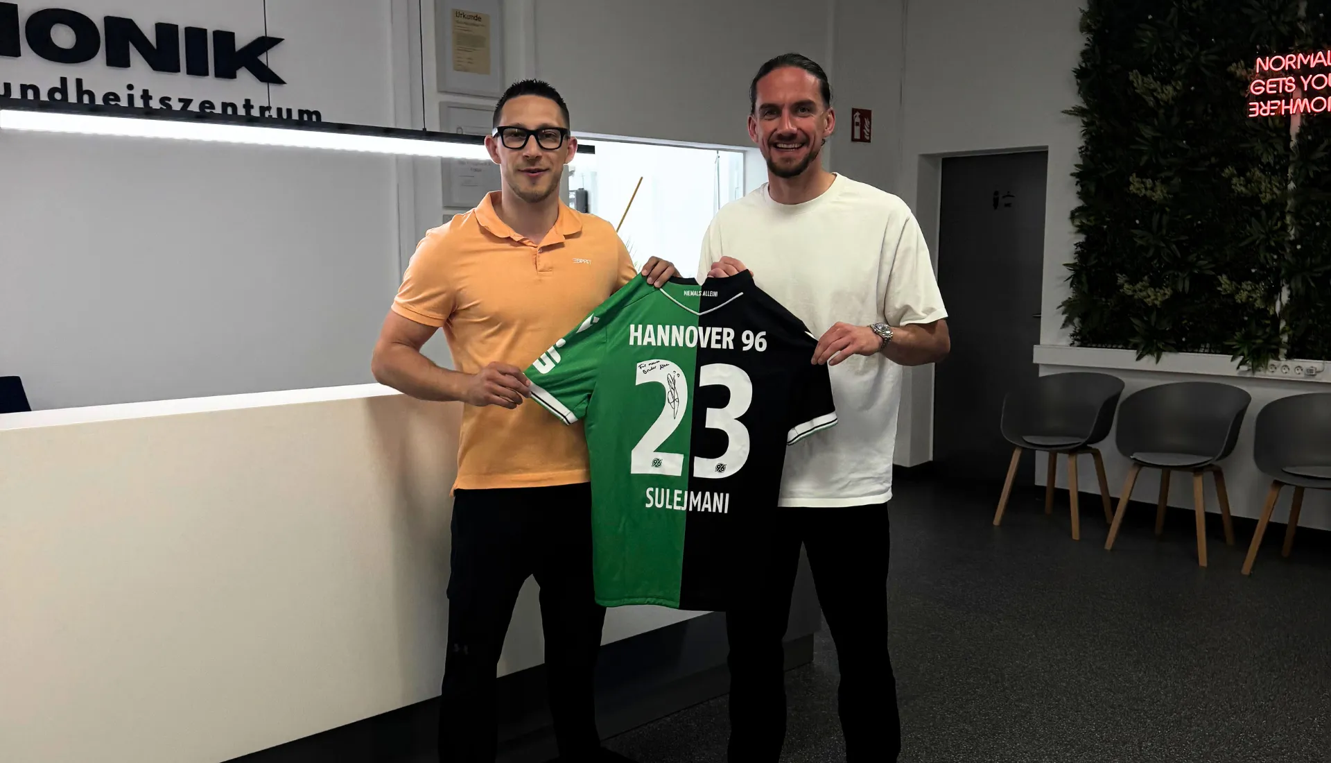BIONIK-Therapeut mit einem Profifußballer und einem signierten Hannover-96-Trikot in der Praxis